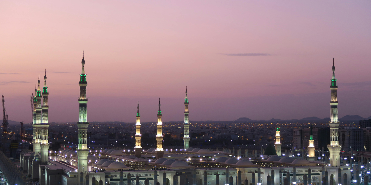 Vue panoramique au coucher du soleil sur les minarets illuminés de la Mosquée du Prophète à Médine, symbolisant les opportunités de voyage avec les différents visas saoudiens pour les Sénégalais.