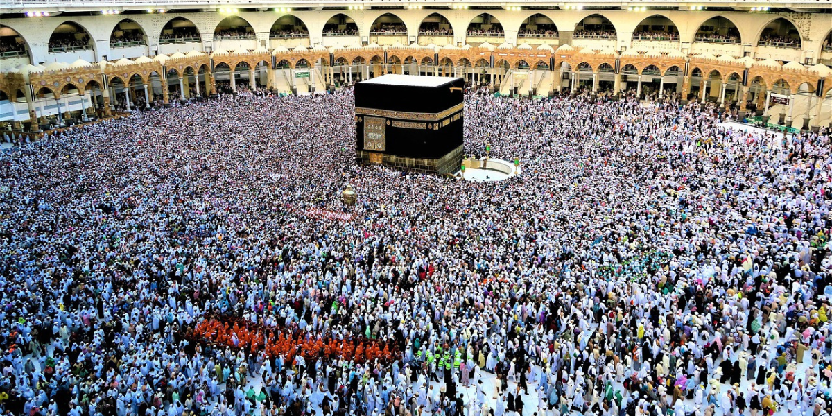 Vue de la Kaaba et de la foule au Masjid al-Haram à la Mecque, illustrant l'isolement émotionnel et les problèmes potentiels lors de la omra de la femme sans mahram.