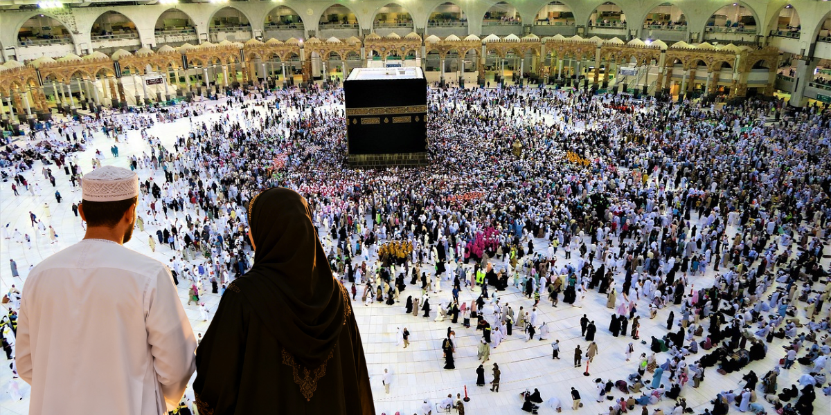 Un homme et une femme devant la Kaaba, symbolisant le soutien logistique et le rôle protecteur du mahram durant la omra de la femme.