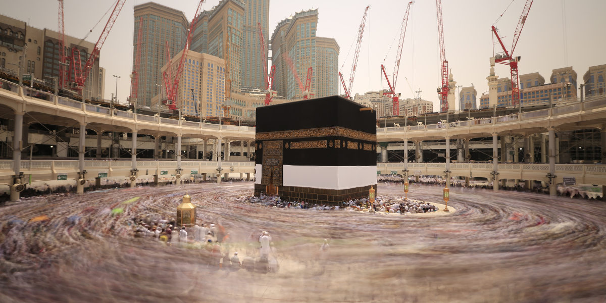 Vue panoramique en pose longue de la Kaaba à Mecca, montrant le mouvement circulaire des pèlerins lors du Tawaf, illustrant le service de Omra Badal par procuration pour honorer un défunt ou un malade.