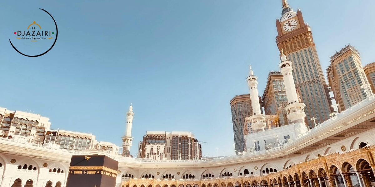 Vue panoramique sur la tour de l'horloge et la Mosquée Al-Haram à La Mecque, avec le logo du Restaurant El Djazairi spécialisé en cuisine traditionnelle.
