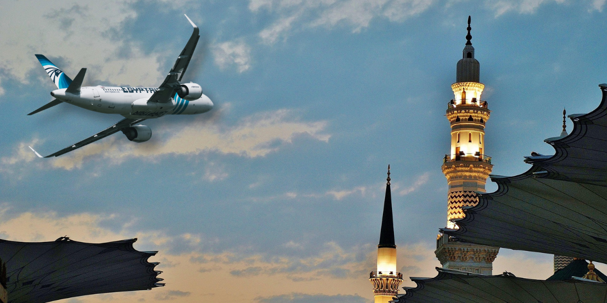 Avion Egypt Air survolant des minarets à la tombée de la nuit, symbolisant l'accompagnement de Direct Mecca pour votre pèlerinage au départ de Lyon.