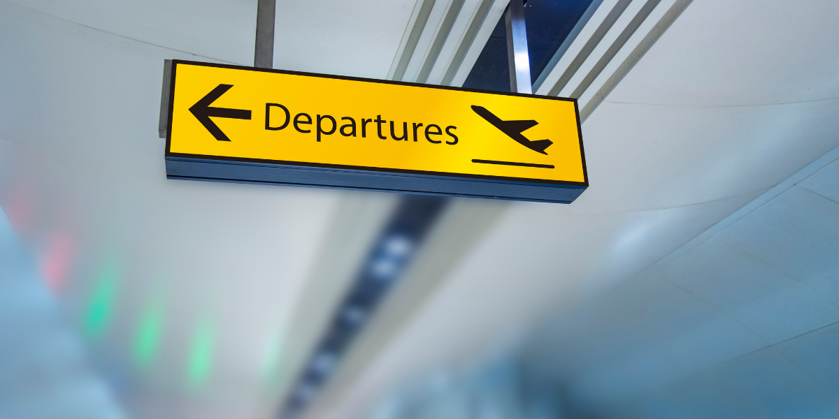 Gros plan sur un panneau jaune 'Departures' à l'aéroport, illustrant les avantages d'une Omra de Lyon avec Royal Jordanian.