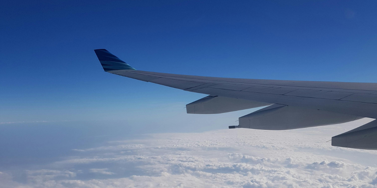 Vue de l'aile d'un avion survolant les nuages, illustrant l'expertise de Direct Mecca pour votre réservation Omra de Lyon avec Royal Jordanian.