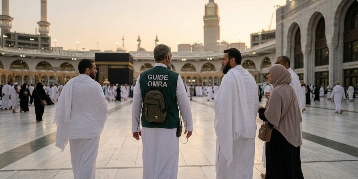Un guide en gilet vert marqué "GUIDE OMRA" échange avec un petit groupe de pèlerins francophones sur l'esplanade du Masjid al-Haram. La scène montre la proximité et l'aspect humain de l'accompagnement personnalisé face à la Kaaba au coucher du soleil.