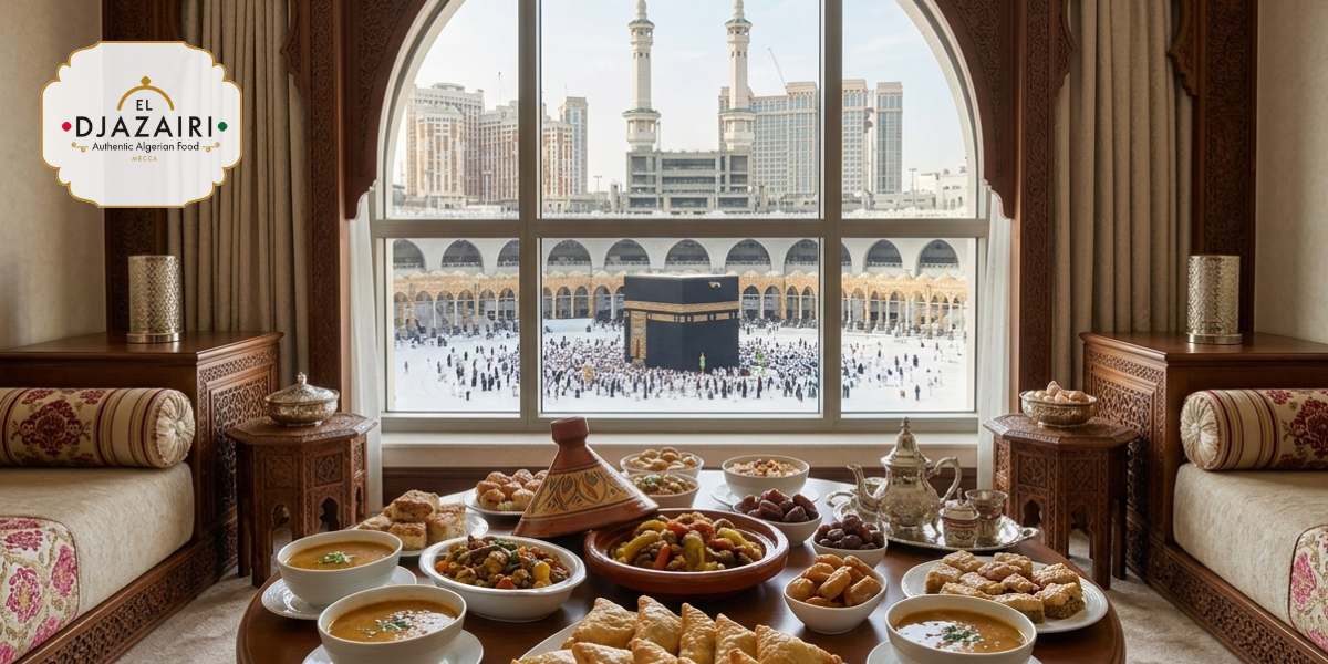 Table dressée avec des plats traditionnels algériens dans un salon luxueux offrant une vue panoramique sur la Kaaba et le Haram, illustrant la gastronomie El Djazairi à La Mecque.