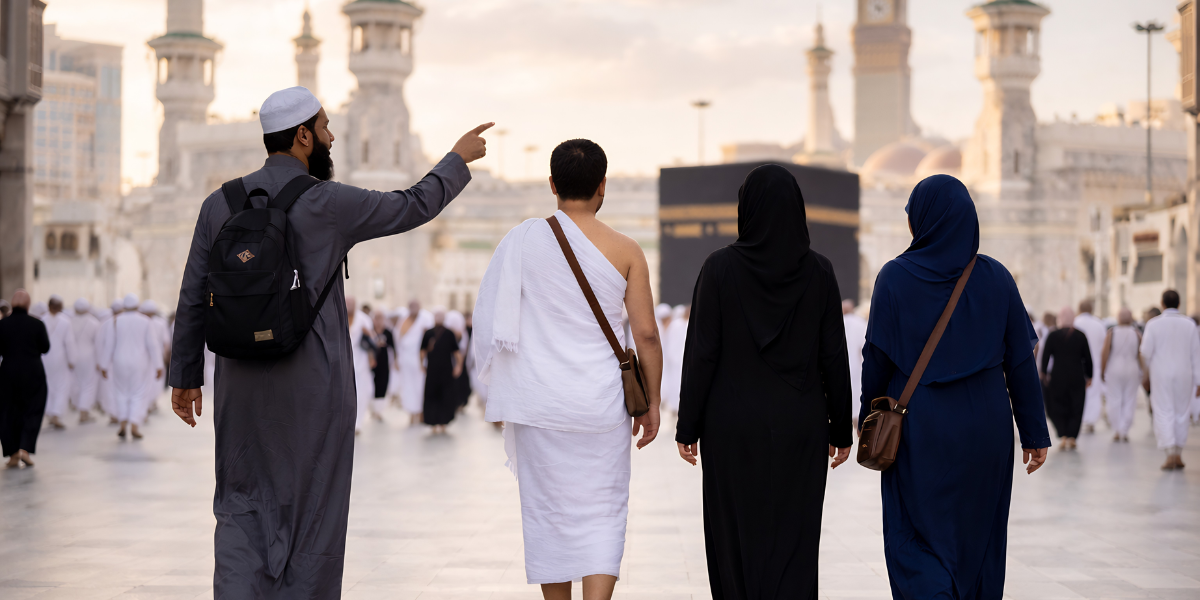 Un guide vêtu d'une tenue traditionnelle grise et portant un sac à dos indique la direction à un groupe composé d'un pèlerin en tenue d'Ihram et de deux femmes, marchant ensemble vers la Kaaba au sein du Masjid al-Haram.