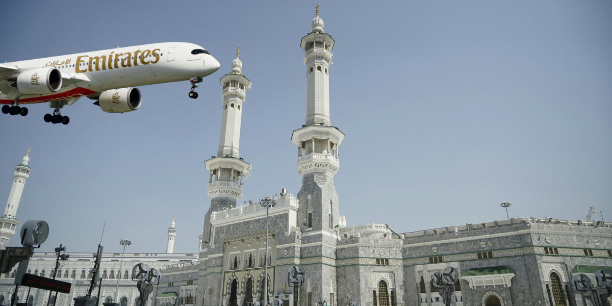 Montage photo montrant un avion Emirates en phase d'approche au-dessus des minarets de la Grande Mosquée de La Mecque, illustrant la gestion complète de votre billet d'avion par Direct Mecca.