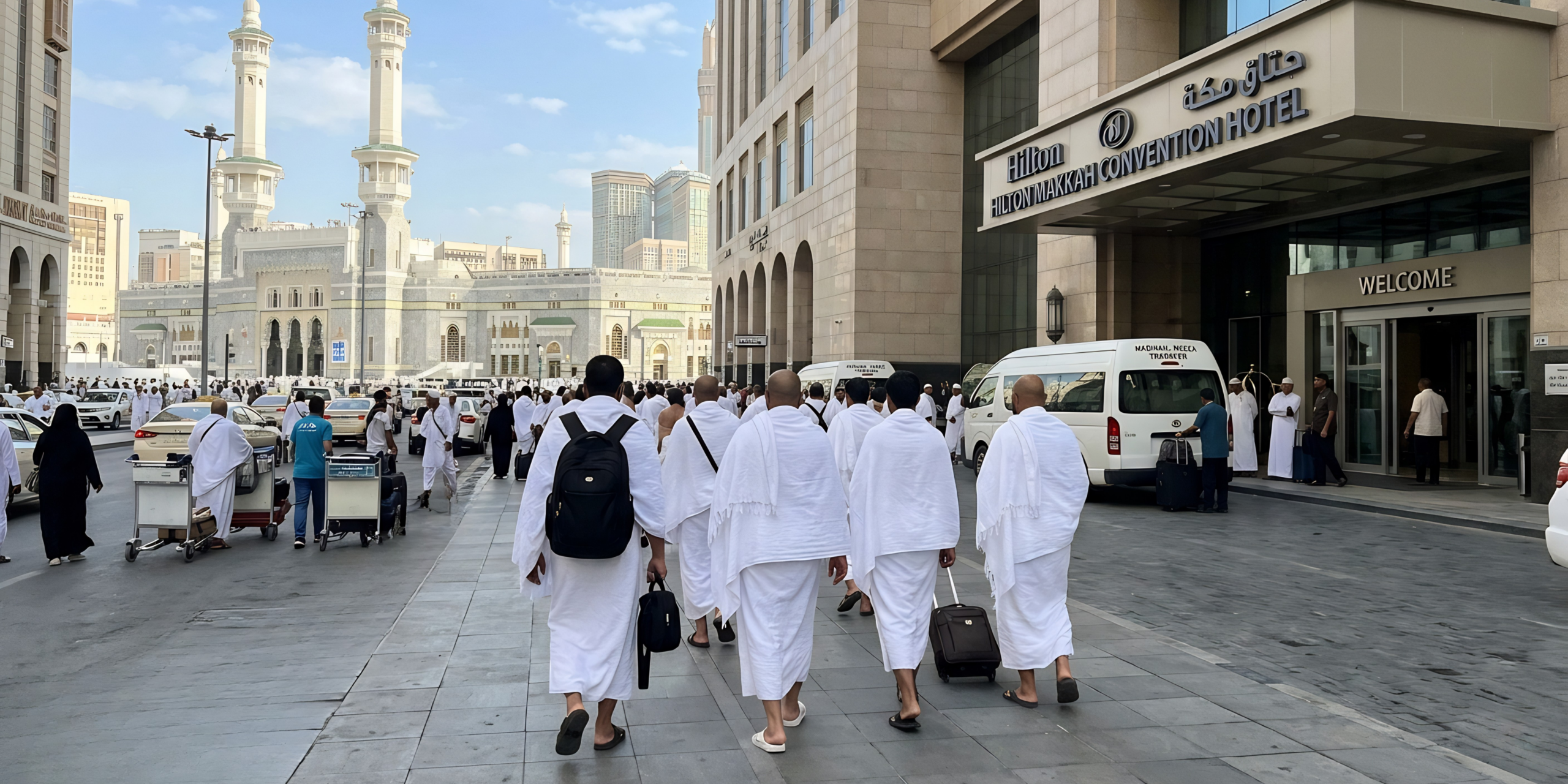 Un groupe de pèlerins en habits d'Ihram arrive à l'hôtel Hilton près du Haram à La Mecque, illustrant la logistique, les transferts fluides et le confort du service d'accompagnement de Direct Mecca.