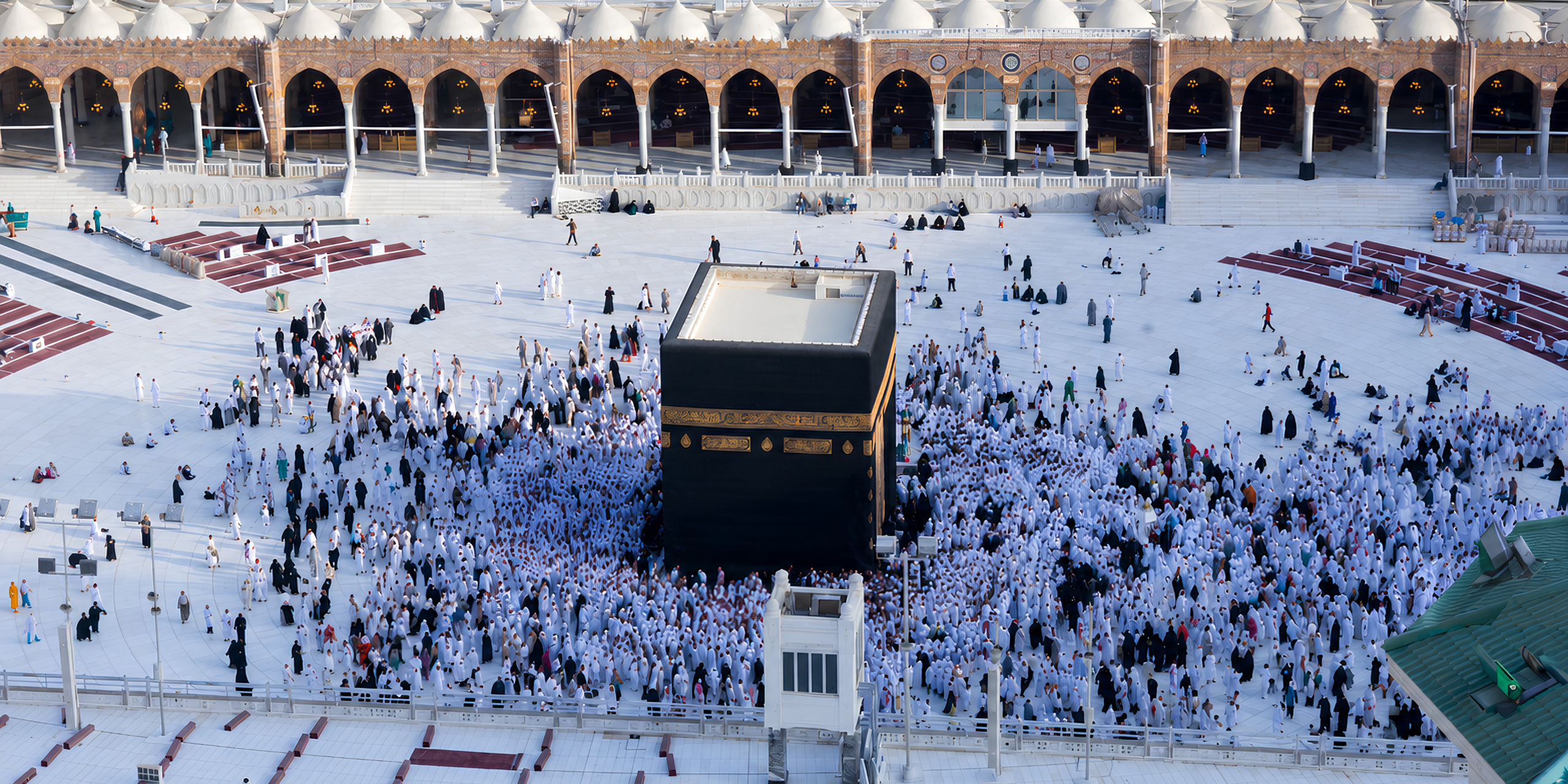 Vue en contre-plongée de la Kaaba entourée de pèlerins dans la cour de Masjid al-Haram, illustrant le rôle essentiel d'un guide expert pour surmonter les défis et éviter les erreurs lors d'une première Omra.
