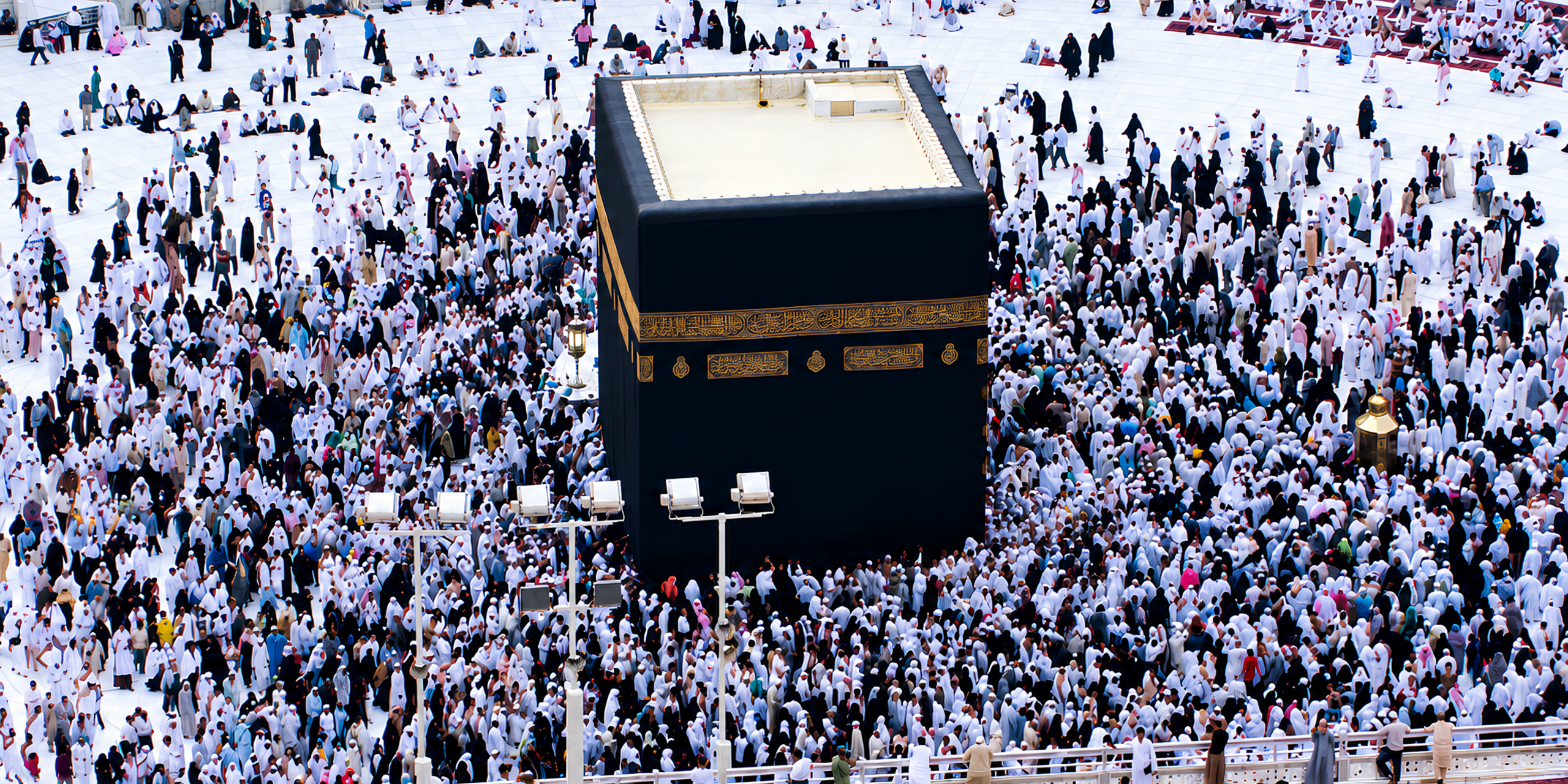 Une vue rapprochée et en plongée de la Kaaba, entourée d'une multitude de pèlerins effectuant les sept tours rituels du Tawaf au sein de la Mosquée sacrée, illustrant l'explication des étapes clés et des rites de l'Omra accompagnés par Direct Mecca.