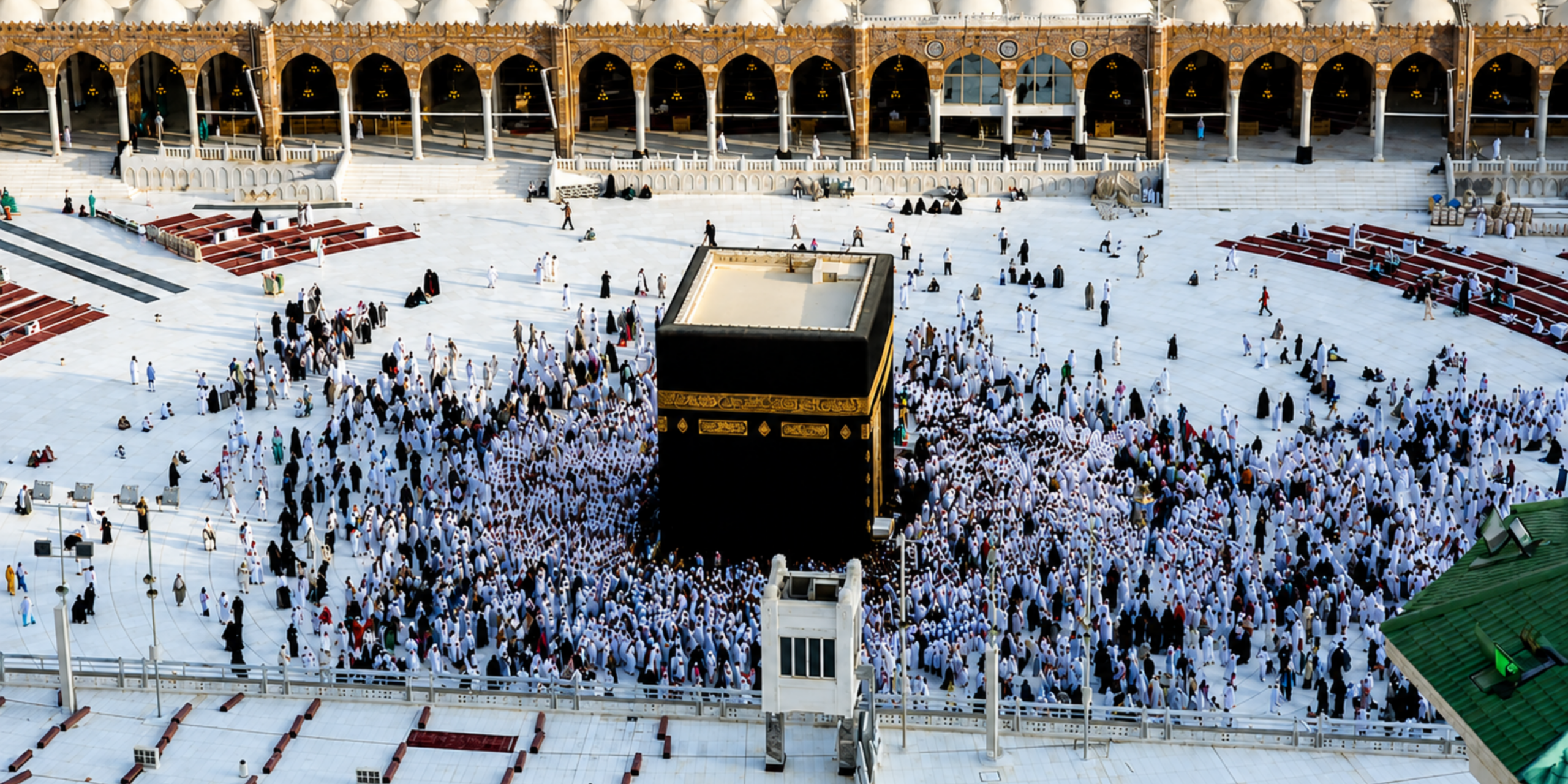 Une vue en plongée et en plein jour de la cour de la Mosquée sacrée à La Mecque, montrant les pèlerins circulant de manière fluide autour de la Kaaba. L'espace dégagé sur l'esplanade illustre parfaitement la baisse d'affluence caractéristique de la saison estivale, idéale pour un voyage hors saison et des rites sereins avec Direct Mecca.