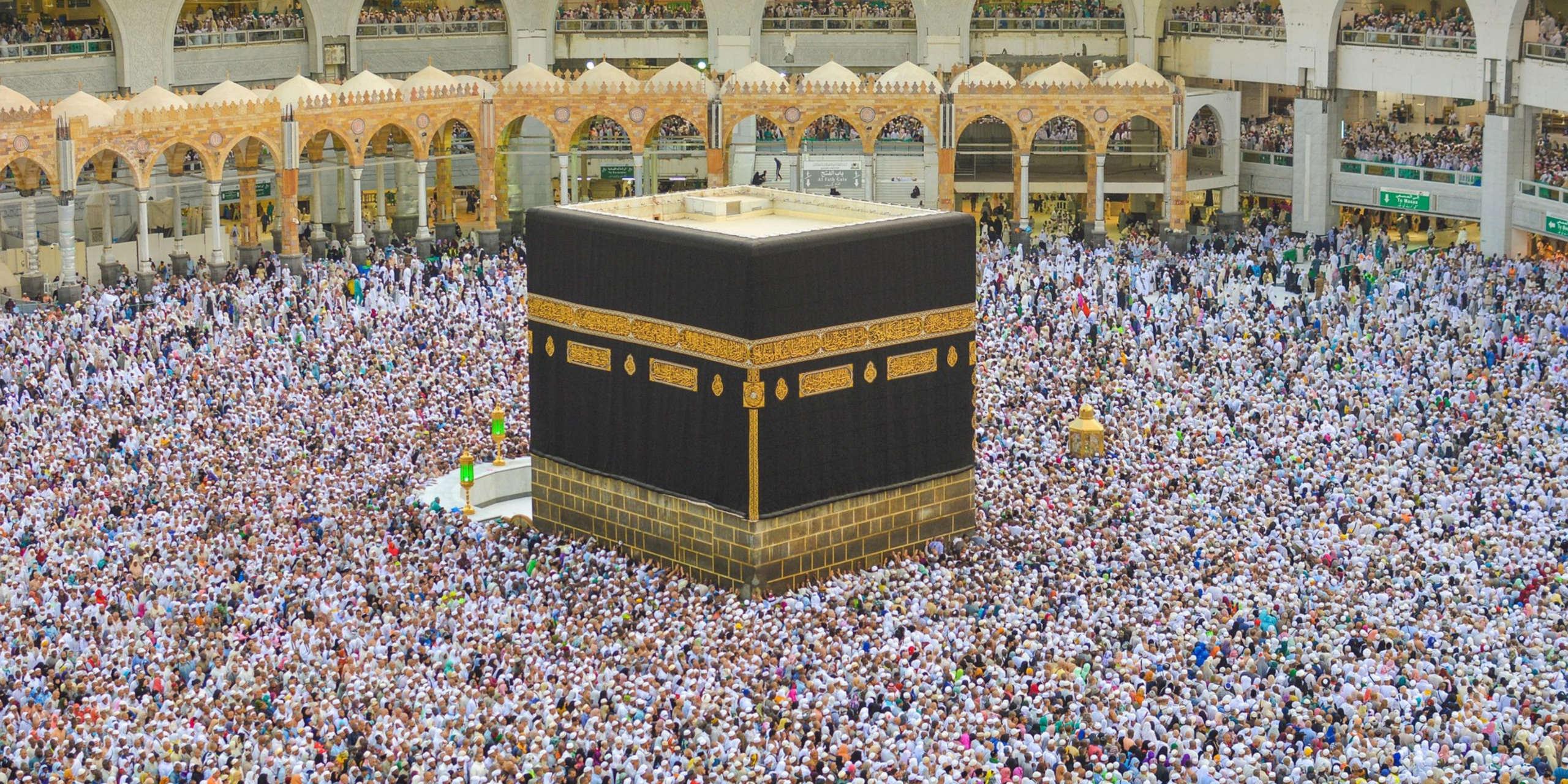 Vue plongeante sur les pèlerins accomplissant les sept circonvolutions du Tawaf autour de la Kaaba, illustrant l'enseignement des rituels par un guide lors de la Omra.