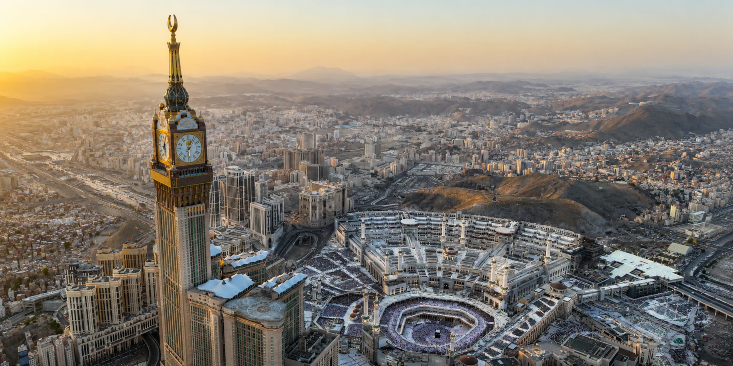 Une vue panoramique aérienne spectaculaire de La Mecque au coucher du soleil, montrant l'immense complexe de la Grande Mosquée (Al-Masjid al-Haram) entourant la Kaaba, dominé par la majestueuse Tour de l'Horloge (Makkah Clock Royal Tower) et les montagnes environnantes, illustrant la prise en charge globale proposée par le Guide Omra express.