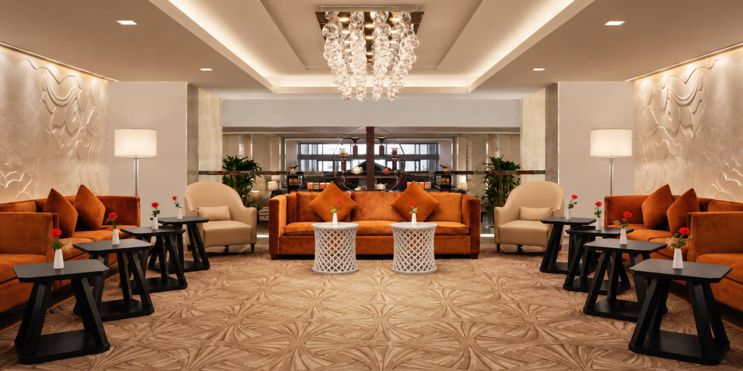 Un salon de repos luxueux et raffiné comprenant d'élégants canapés en velours orange, des fauteuils beige et des tables d'appoint décorées de roses, illustrant les espaces de détente et les prestations haut de gamme de l'Hôtel Conrad Jabal Omar Makkah.