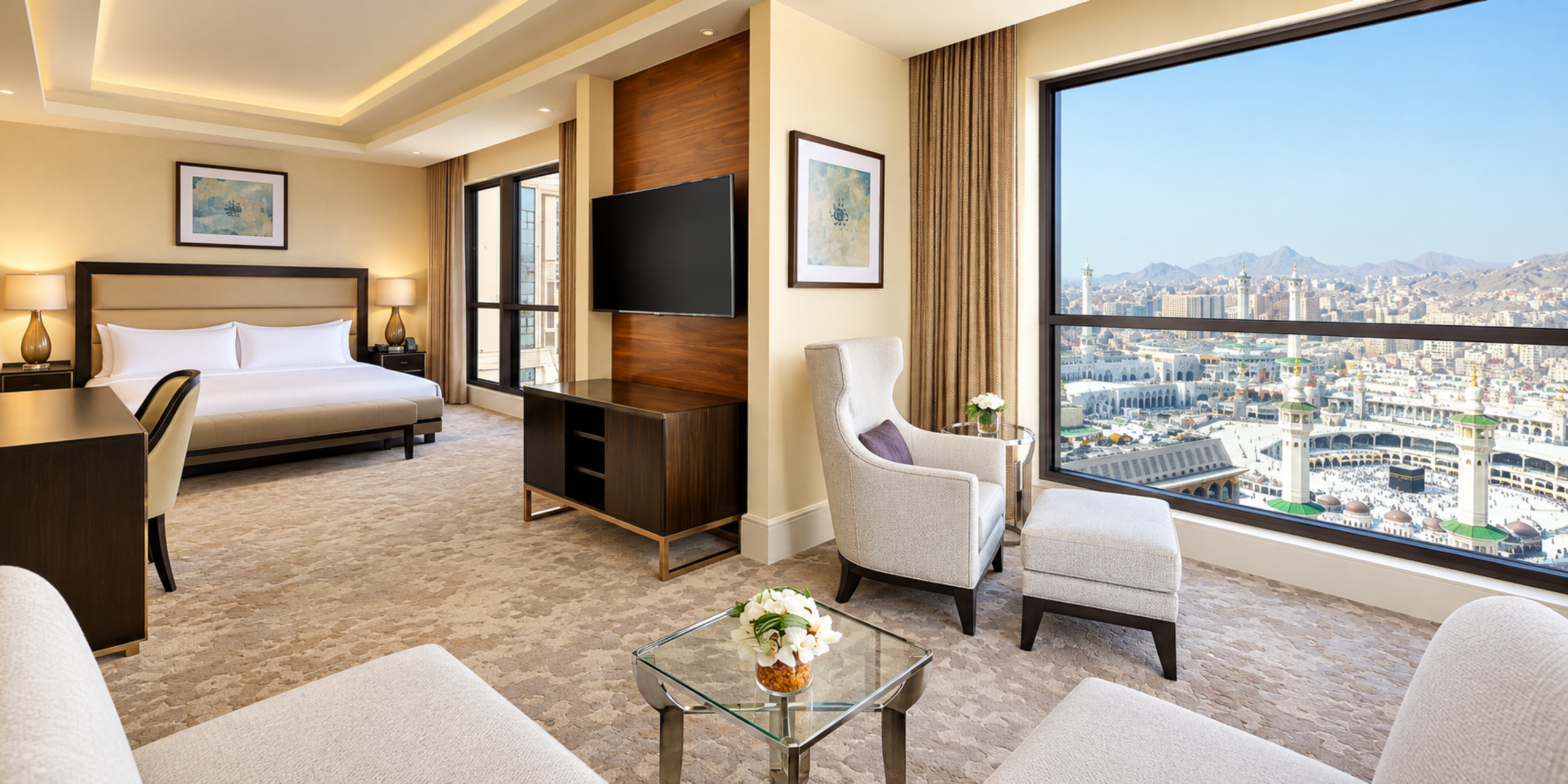 Une suite exécutive luxueuse offrant un espace salon avec fauteuils et une grande baie vitrée panoramique sur la Kaaba et le Masjid Al-Haram, illustrant le rapport qualité-prix et l'expérience haut de gamme de l'Hôtel Conrad Jabal Omar Makkah.
